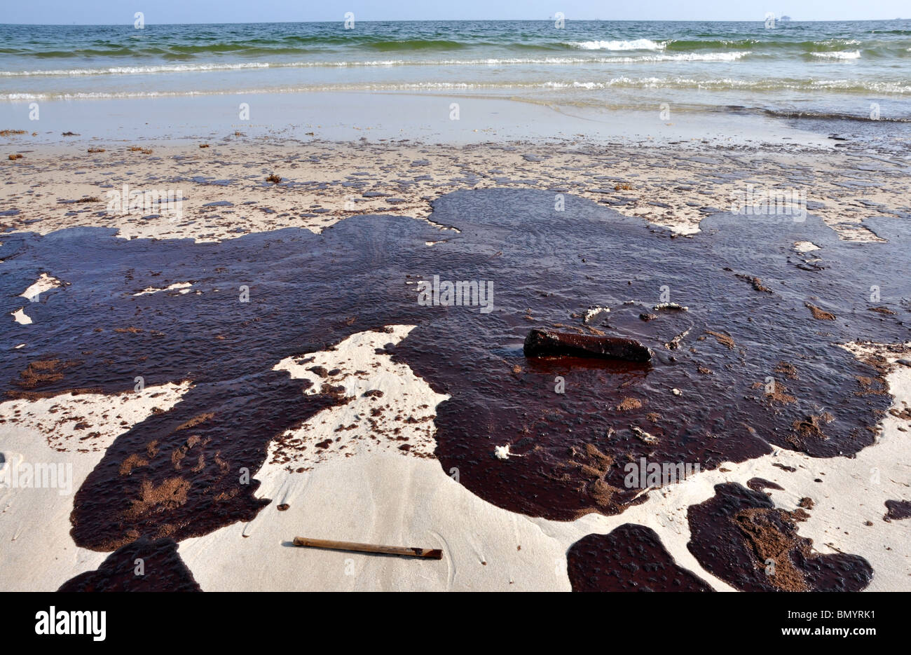 Ölpest am Strand mit off Shore Bohrinsel im Hintergrund. Stockfoto