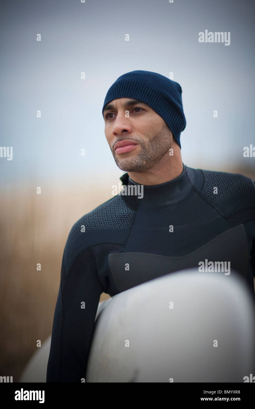 Afrikanische amerikanische Mann im Taucheranzug tragen Surfbrett Stockfoto