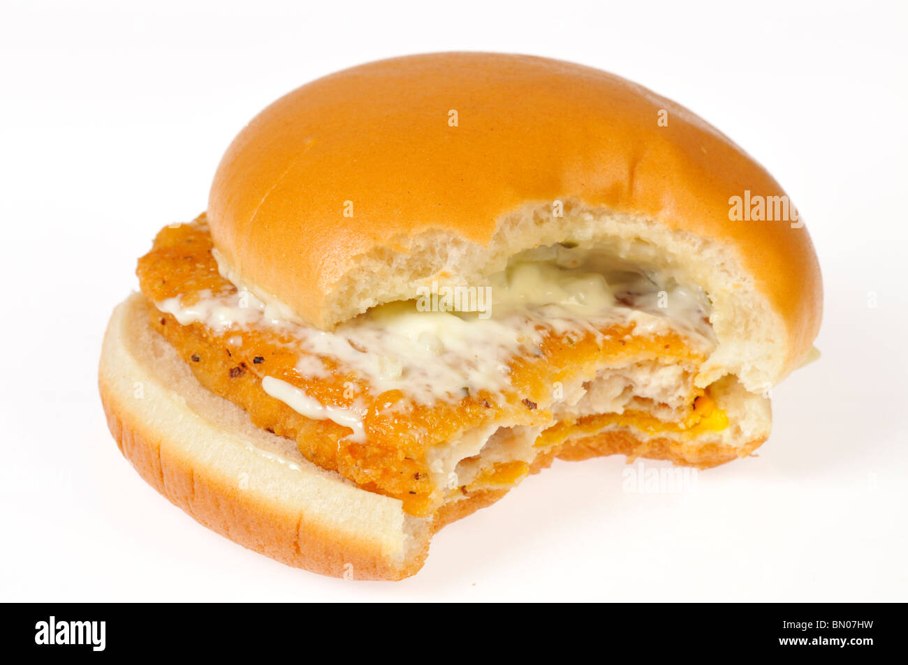 Filet vom Fisch-Sandwich mit Käse und bedeckt mit Remoulade auf Brötchen mit Biss genommen auf weißem Hintergrund, Ausschnitt. Stockfoto