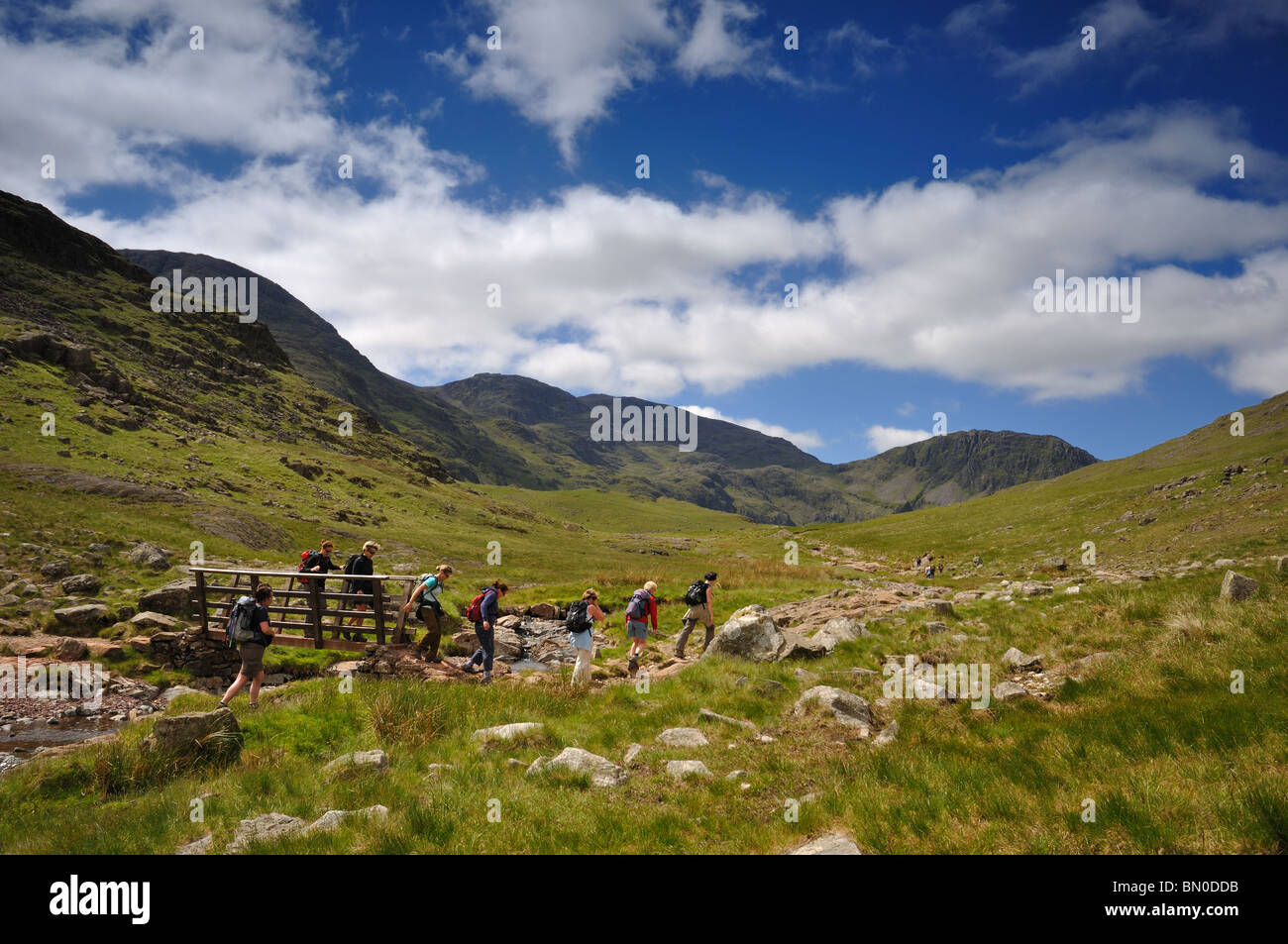 Eine Gruppe von Wanderern durchqueren Sty Head Gill im Lake district Stockfoto