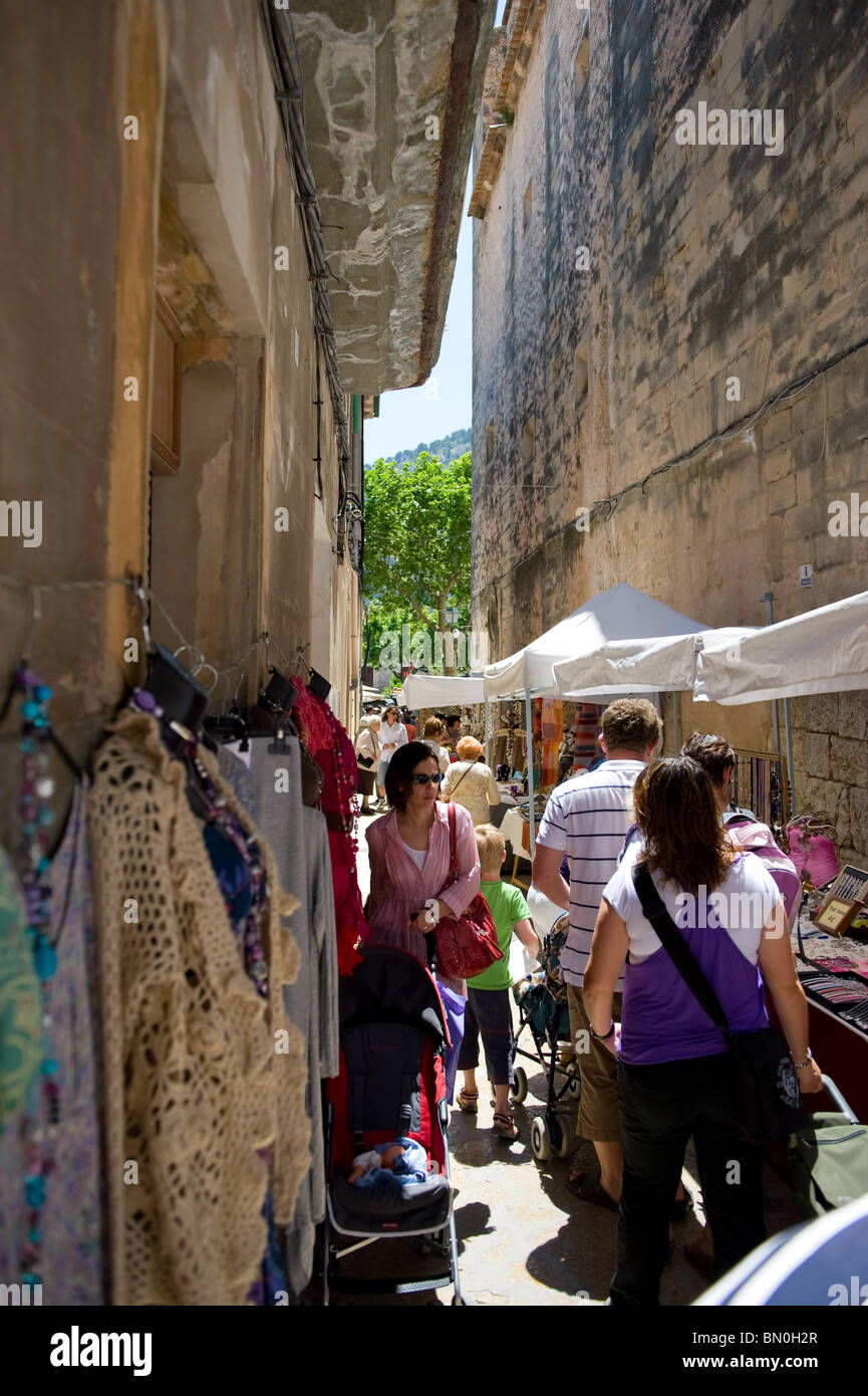 Touristen gehen und Einkaufen in einer schmalen Seitenstraße am Sonntagsmarkt in der Altstadt von Pollença, Mallorca 2010 Stockfoto