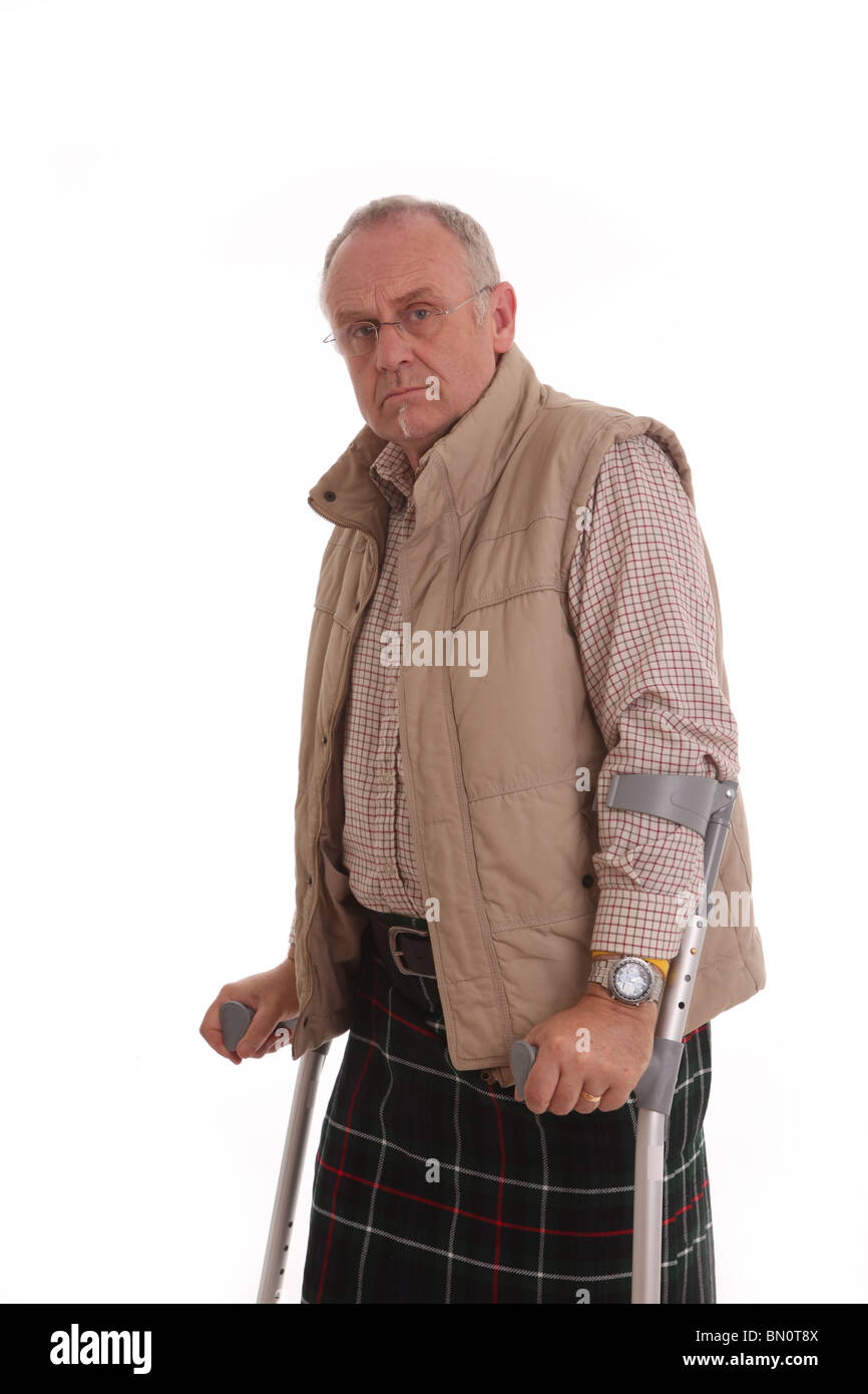 Scotsman gekleidet für den Außenbereich auf Krücken Stockfoto
