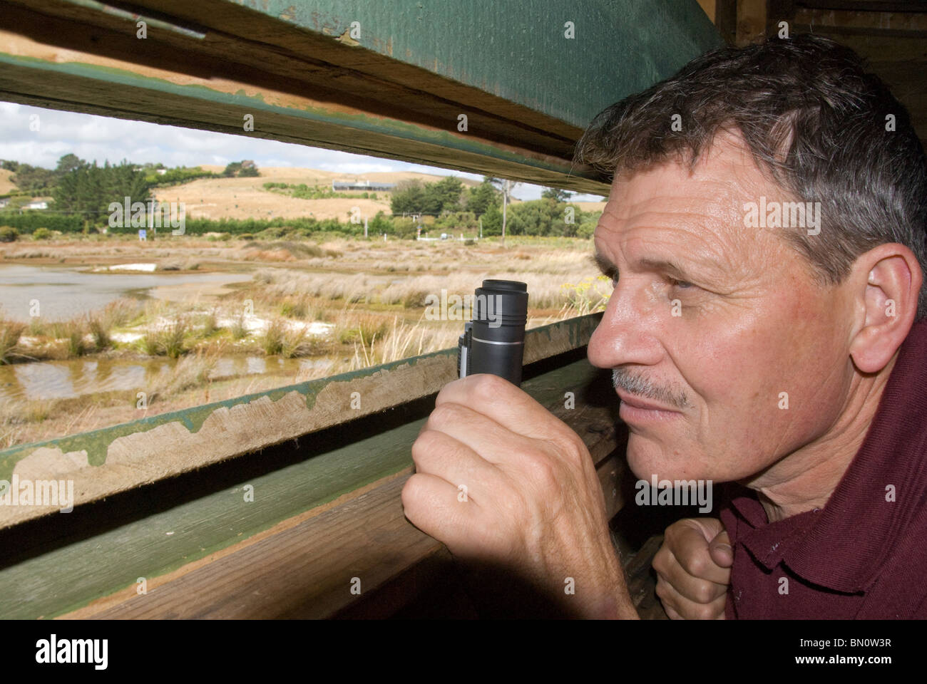 Mann in Hut mit einem Fernglas, 50er Jahre beobachten Vögel bei Wildlife Reserve, Pauatahanui Inlet, Wellington, Nordinsel, Neuseeland Stockfoto