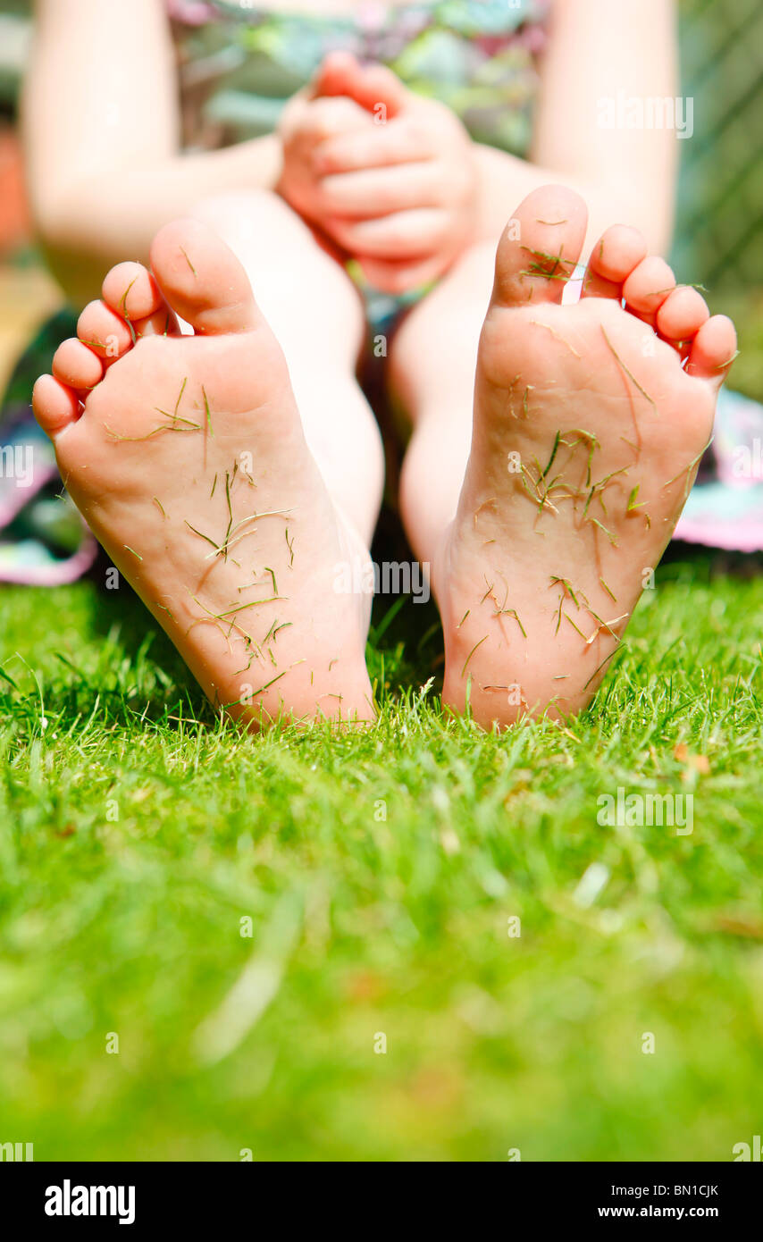 Vier Jahre altes Mädchen in einem Garten mit Rasen Stecklinge an den Sohlen ihrer Füße. Stockfoto