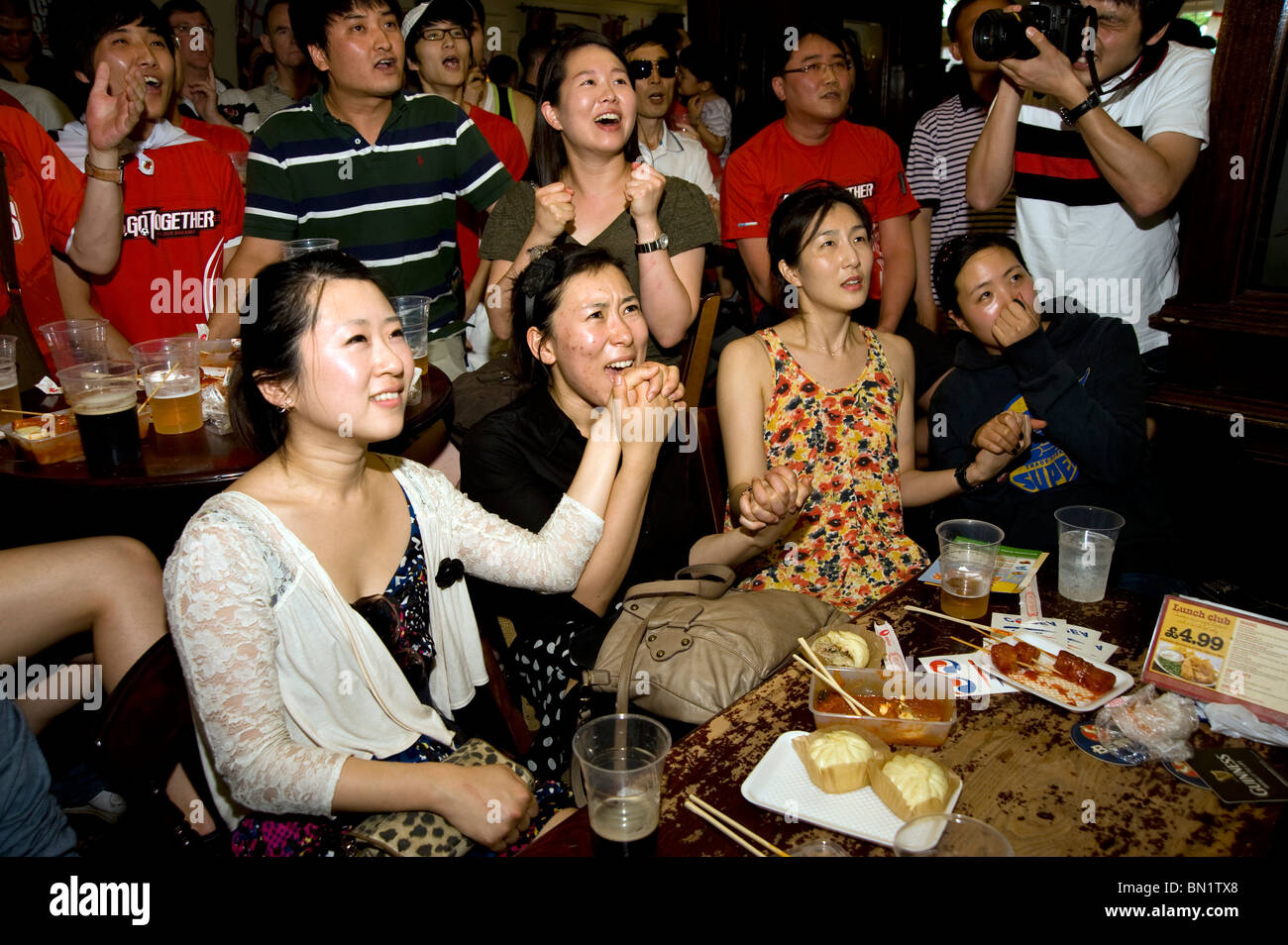 Weibliche südkoreanischen Fußball-Fans, die Hand in Hand beim Betrachten ihrer Team-Spiel gegen Uruguay in einem Londoner Pub während der Stockfoto