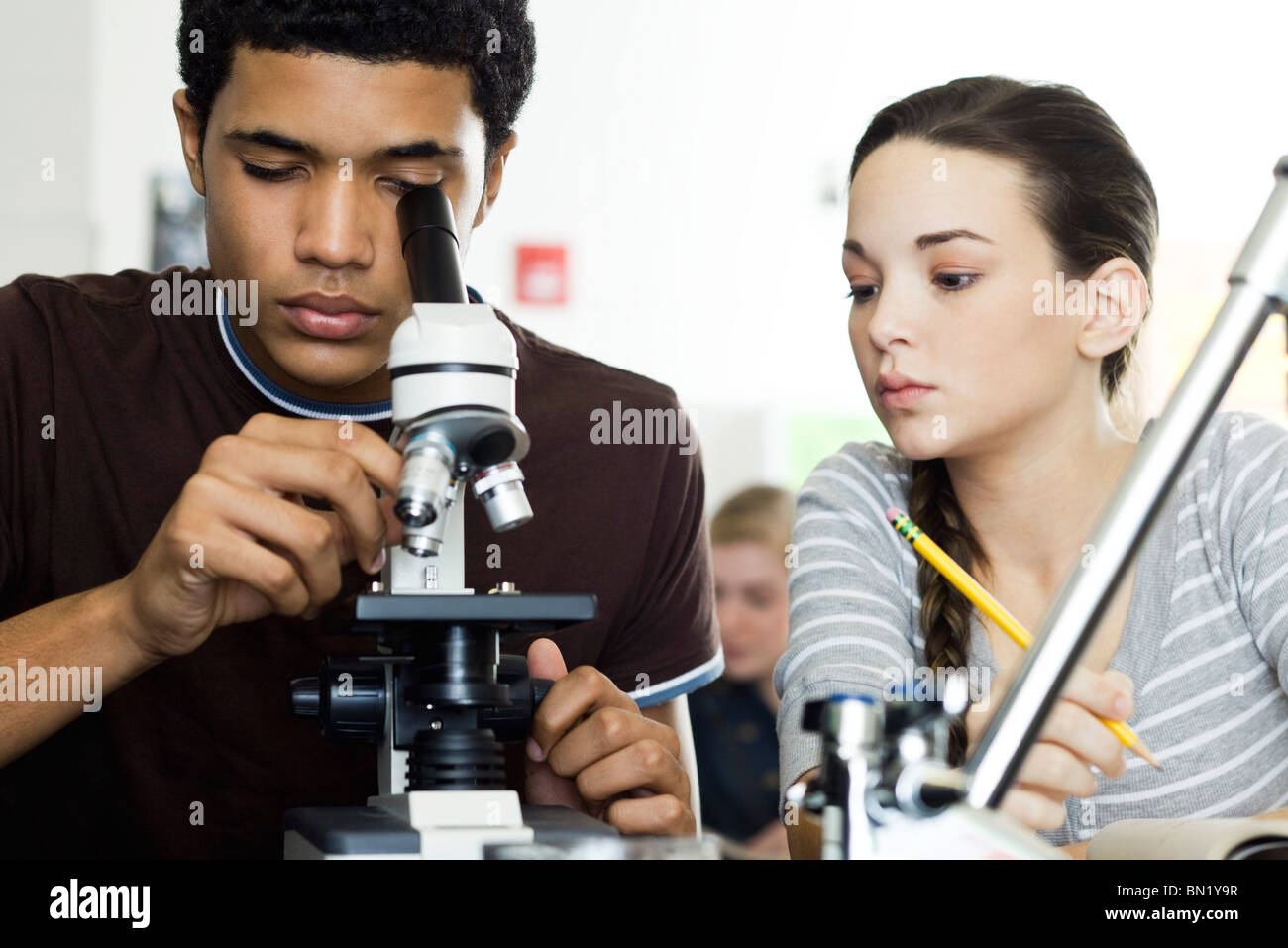 Student auf der Suche durch Mikroskop im naturwissenschaftlichen Unterricht Stockfoto