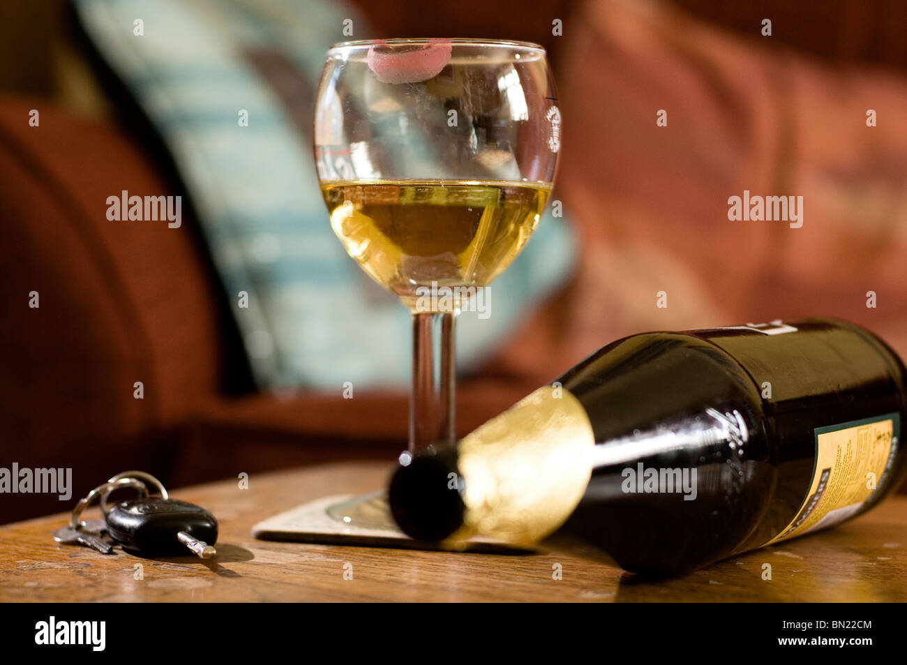 Ein Glas Bier mit einem Lippenstift Mark auf weiter, um auf einen Satz von Autoschlüssel und eine leere Flasche auf seiner Seite unscharf Stockfoto
