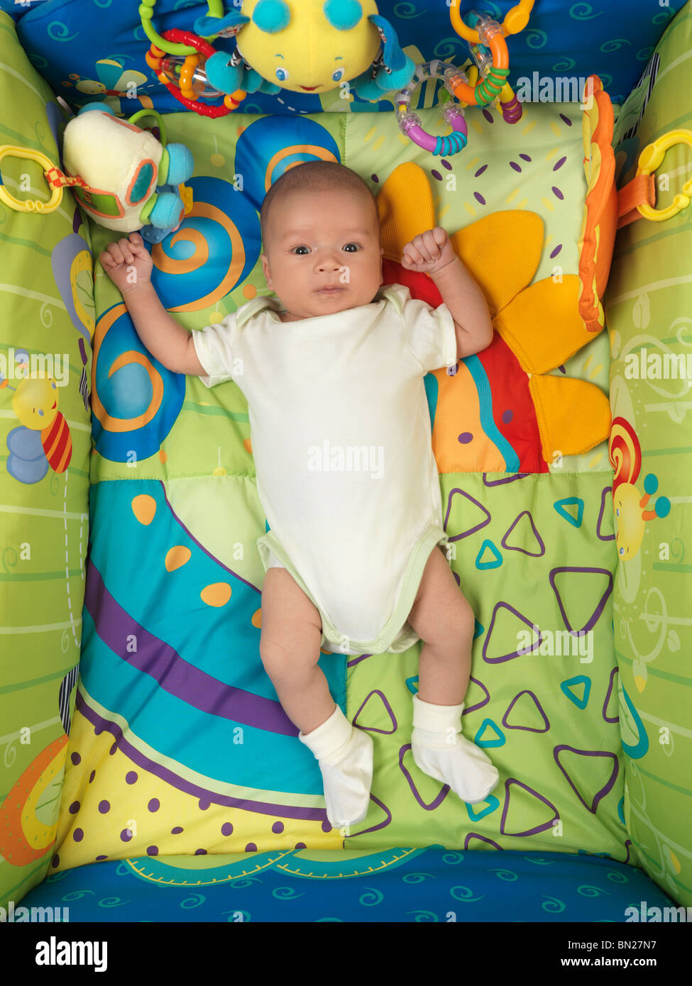Sechs Wochen alten niedlichen Baby junge liegend in eine bunte Spielmatte mit Spielzeug Stockfoto