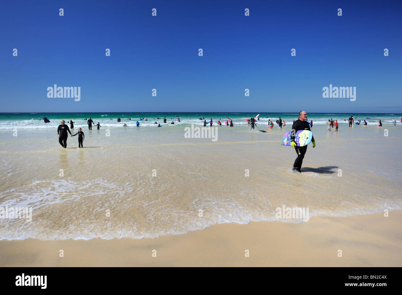 Schwimmer und Surfer genießen Sie einen sonnigen Tag und ein klares Meer Stockfoto
