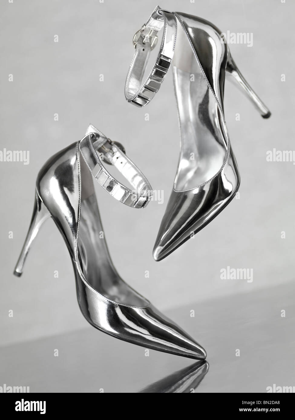 Stilvolle glänzend silberne Stiletto high Heel Schuhe fallen auf Metalloberfläche Stockfoto