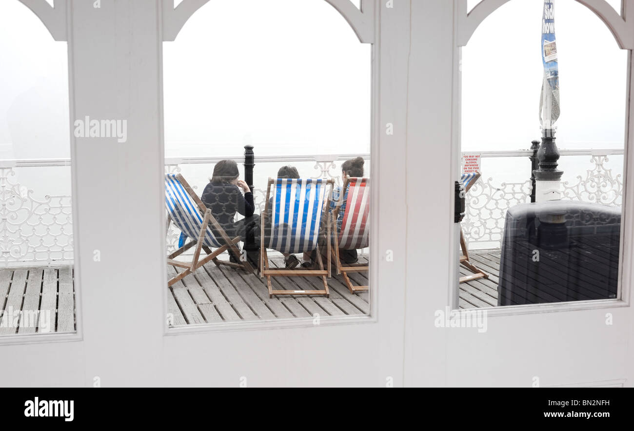 Durch die Glasfenster von Brighton Pier Touristen gesehen sitzen auf den Liegestühlen Stockfoto