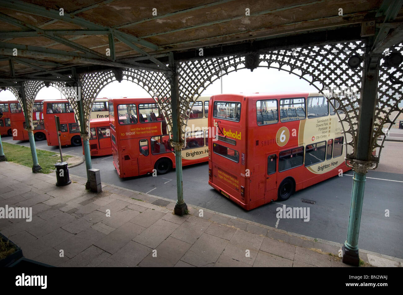 Eine Reihe von Brighton & Hove Bus und Coach Unternehmen Doppeldecker Busse stehen unter den verzierten Bögen in Madeira Drive in Brighton Stockfoto