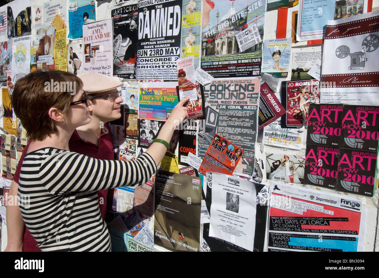 Festivalbesucher Blick auf eine Wand bedeckt mit Flieger für Bands, Theater, Kunst und Veranstaltungen Brighton Festival 2010 Stockfoto