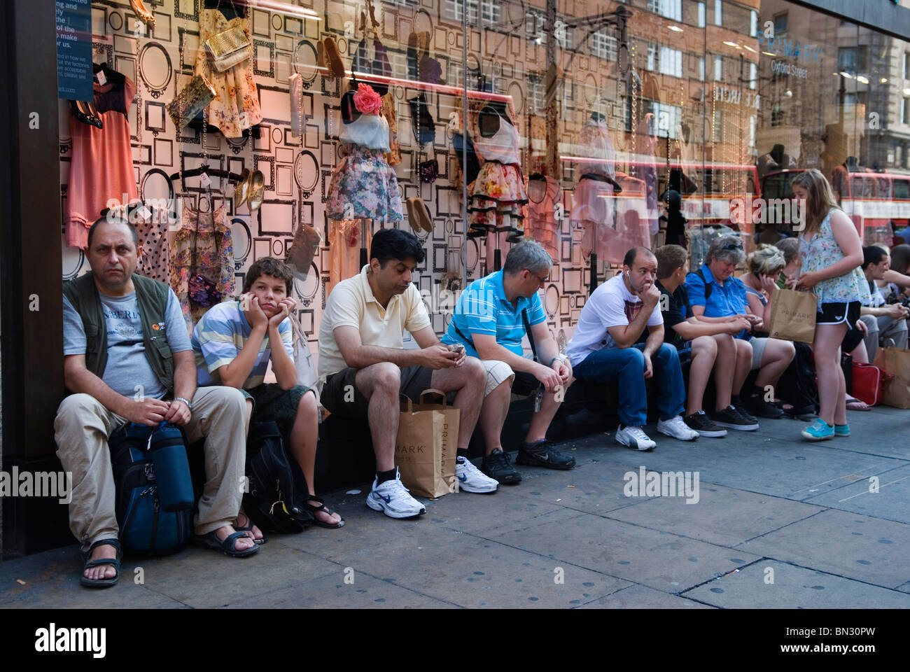 Oxford Street London. Müde erschöpfte Männer sitzen auf der Bank vor dem Primark Kaufhaus, während ihre Partner im Inneren einkaufen. UK 2010 HOMER SYKES Stockfoto