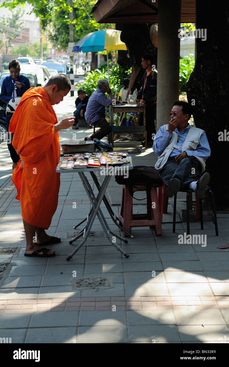 Buddhistischer Mönch trägt einen orangefarbenen Gewand und Kauf einer Uhr in einer Straße von Chiang Mai, Thailand Stockfoto