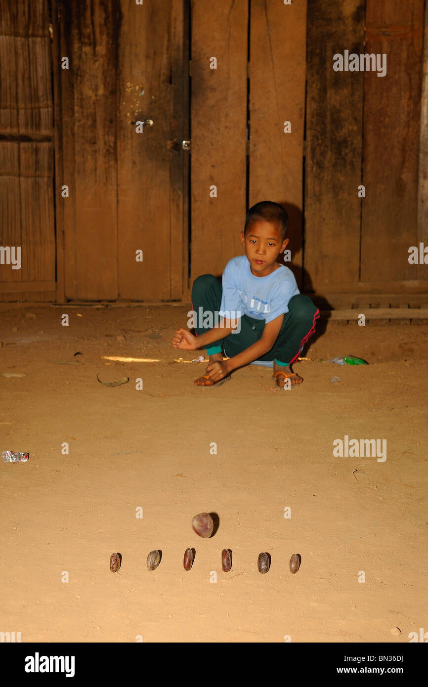 Young Black Lahu junge spielt mit Steinen auf dem Boden, Bergstämme von Mae Hong Son, Nord-Thailand, Asien Stockfoto