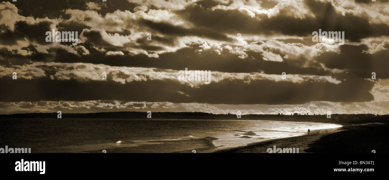 einzelne kleine Figur am Meer mit starken Himmel Stockfoto