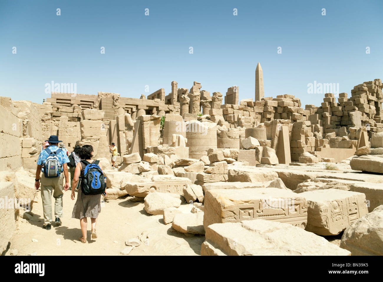 Touristen, die zu Fuß durch die zerstörten großen Tempel von Karnak in Luxor, Ägypten Stockfoto