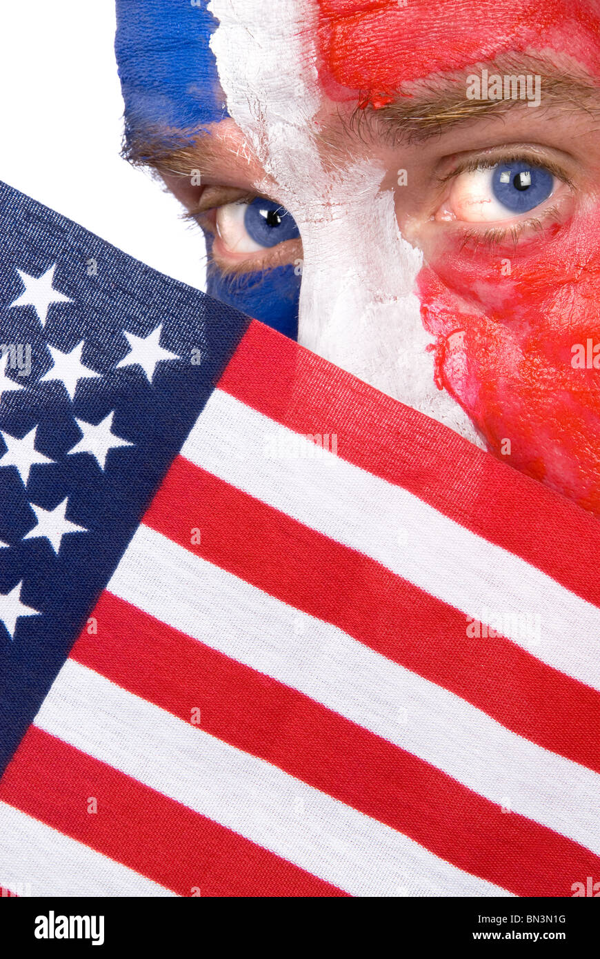 Ein patriotischer Mann mit Gesichtsbemalung lugt über eine amerikanische Flagge Stockfoto