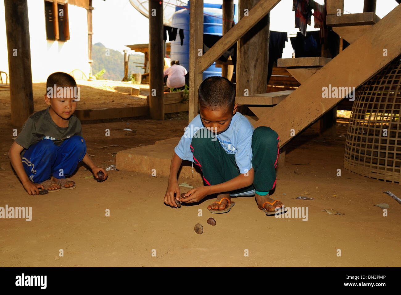 Young Black Lahu Jungs spielen mit Steinen auf dem Boden, hill Tribe von Mae Hong Son, Nord-Thailand, Asien Stockfoto