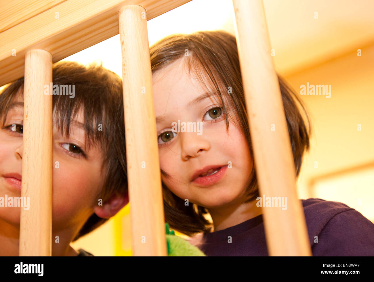 Mädchen und Jungen auf der Suche durch ein Holzgeländer low angle View Stockfoto