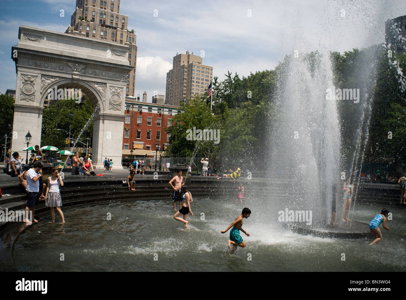 Kinder und Erwachsene erfrischen Sie sich in dem renovierten Brunnen im Washington Square Park in Greenwich Village in New York Stockfoto