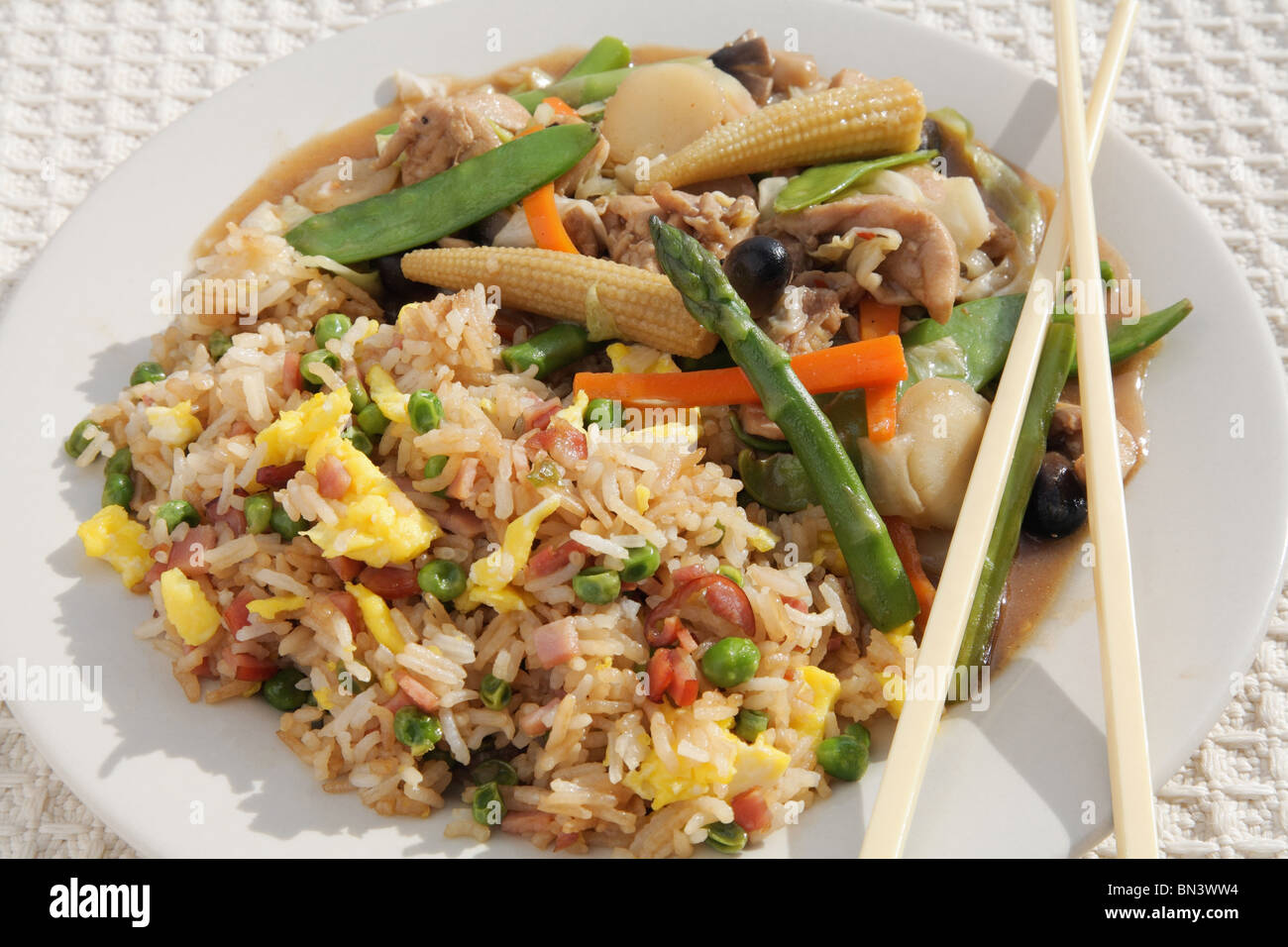 Nahaufnahme Teller mit bunten chinesischen Hühnchen und Gemüserührern braten Mahlzeit mit Essstäbchen Stockfoto