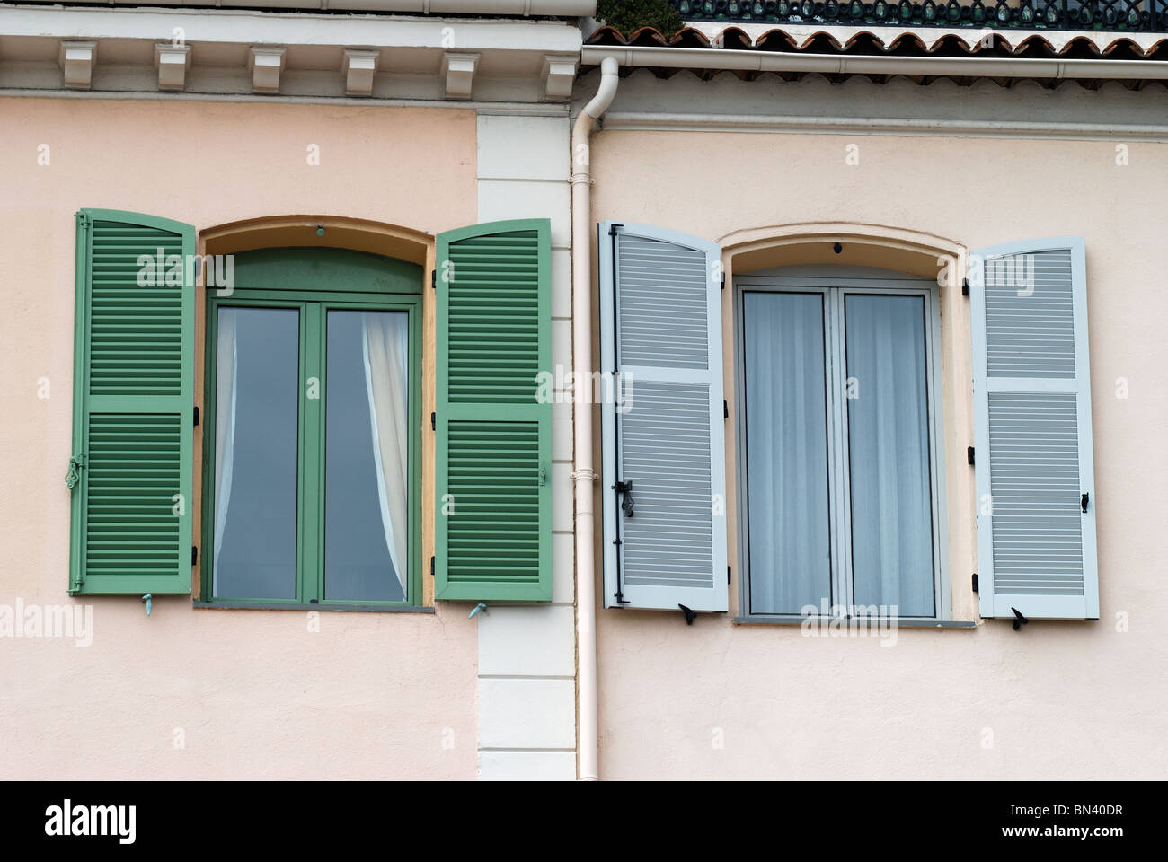 Fenster mit zwei verschiedenen farbigen Rahmen und Fensterläden, Mehrfamilienhaus in Cannes. Cote d ' Azur. Frankreich Stockfoto