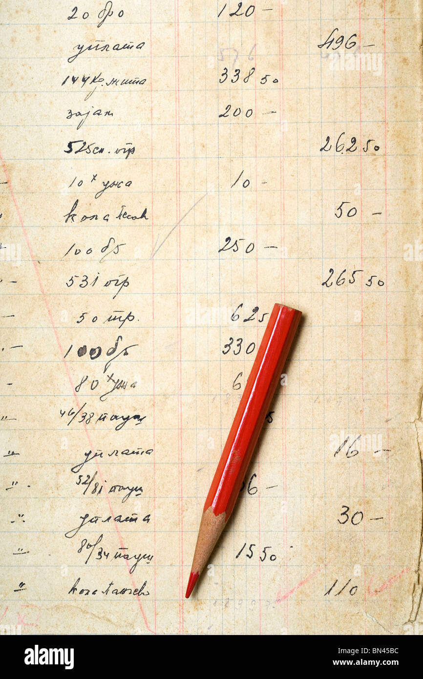 ein roter Buntstift auf vergilbtem Papier mit Buchhaltungszahlen Stockfoto