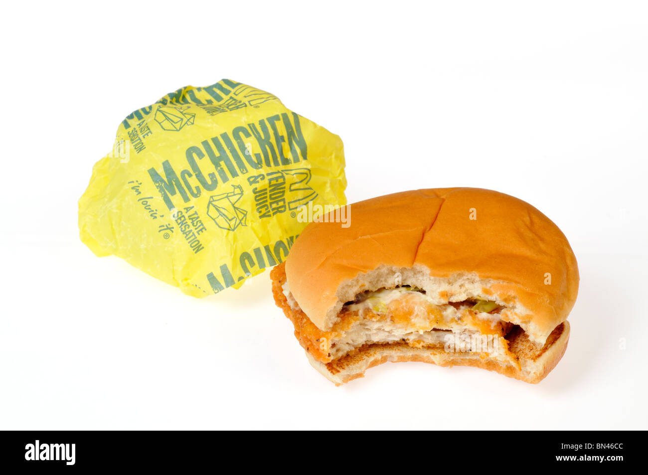McDonald's McChicken mit einem Bissen aus ihm heraus mit Papierverpackung auf weißem Hintergrund genommen. Schneiden Sie aus. Stockfoto