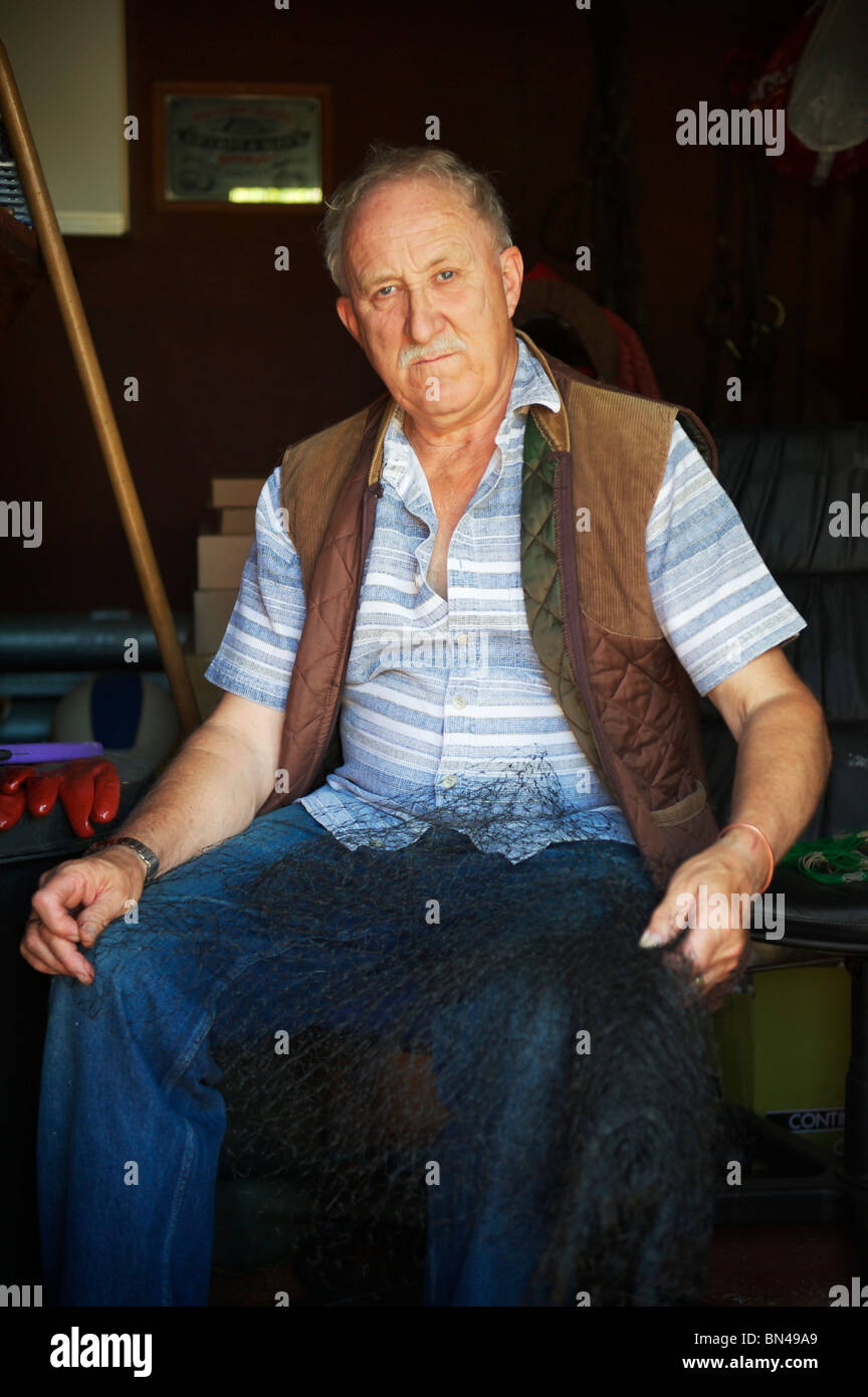grauen Haaren älterer Bauer sitzt in seinem Schuppen gedrückter Netting bereit für den Anbau in Zuteilung Stockfoto