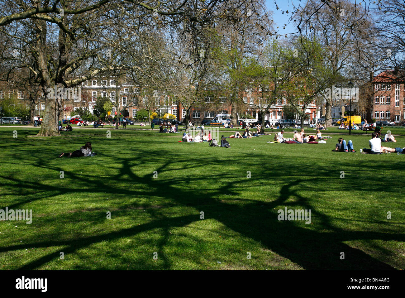 Sonnenanbeter genießen die Frühlingssonne auf Parsons Green, Fulham, London, UK Stockfoto