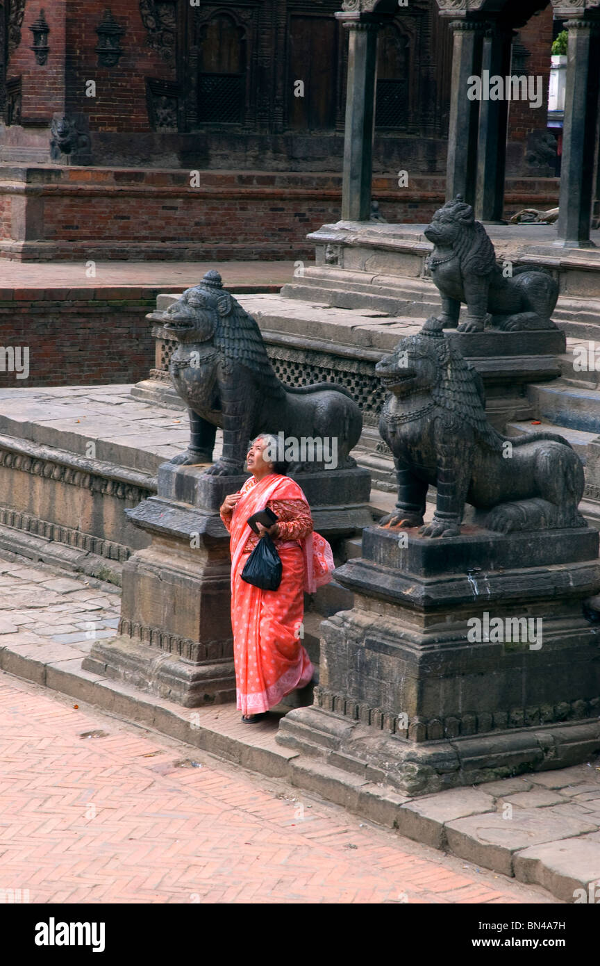 Eine ältere Dame liegt am Eingang zum Krishna Mandir, Durbar Square, Patan, Nepal. Stockfoto