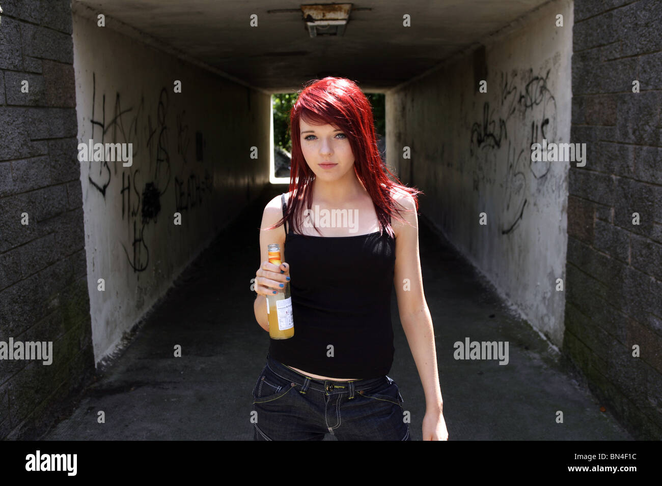 Teenager-Mädchen trinken eine Flasche Alkohol außerhalb in der Nähe eine Unterführung. Stockfoto