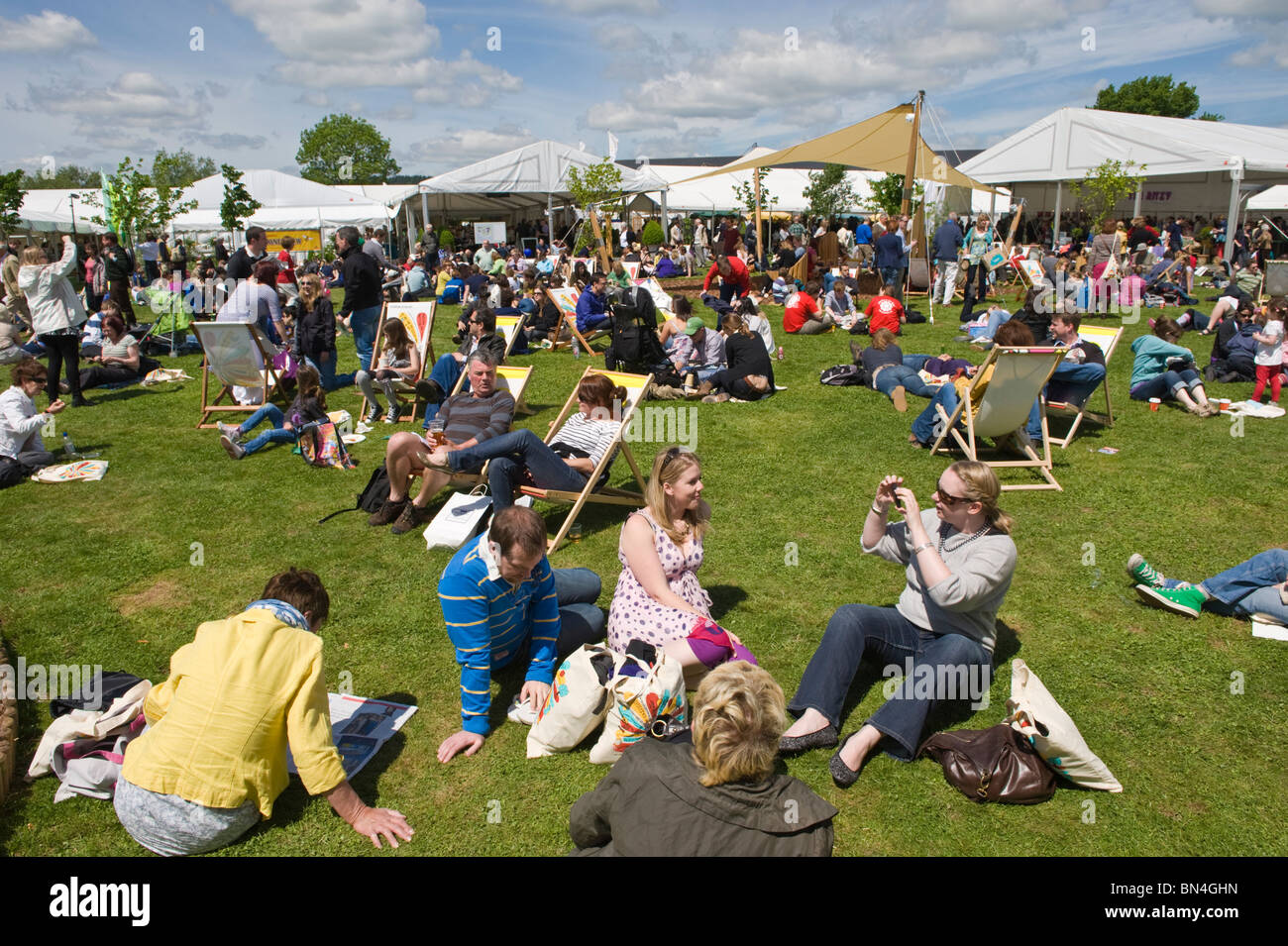 Massen von Menschen, die entspannen, sitzen auf dem Rasen in der Sommersonne am Hay Festival 2010 Hay on Wye Powys Wales UK Stockfoto