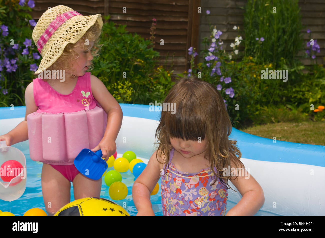 Zwei junge weibliche Kinder spielen In A Paddling pool Stockfoto
