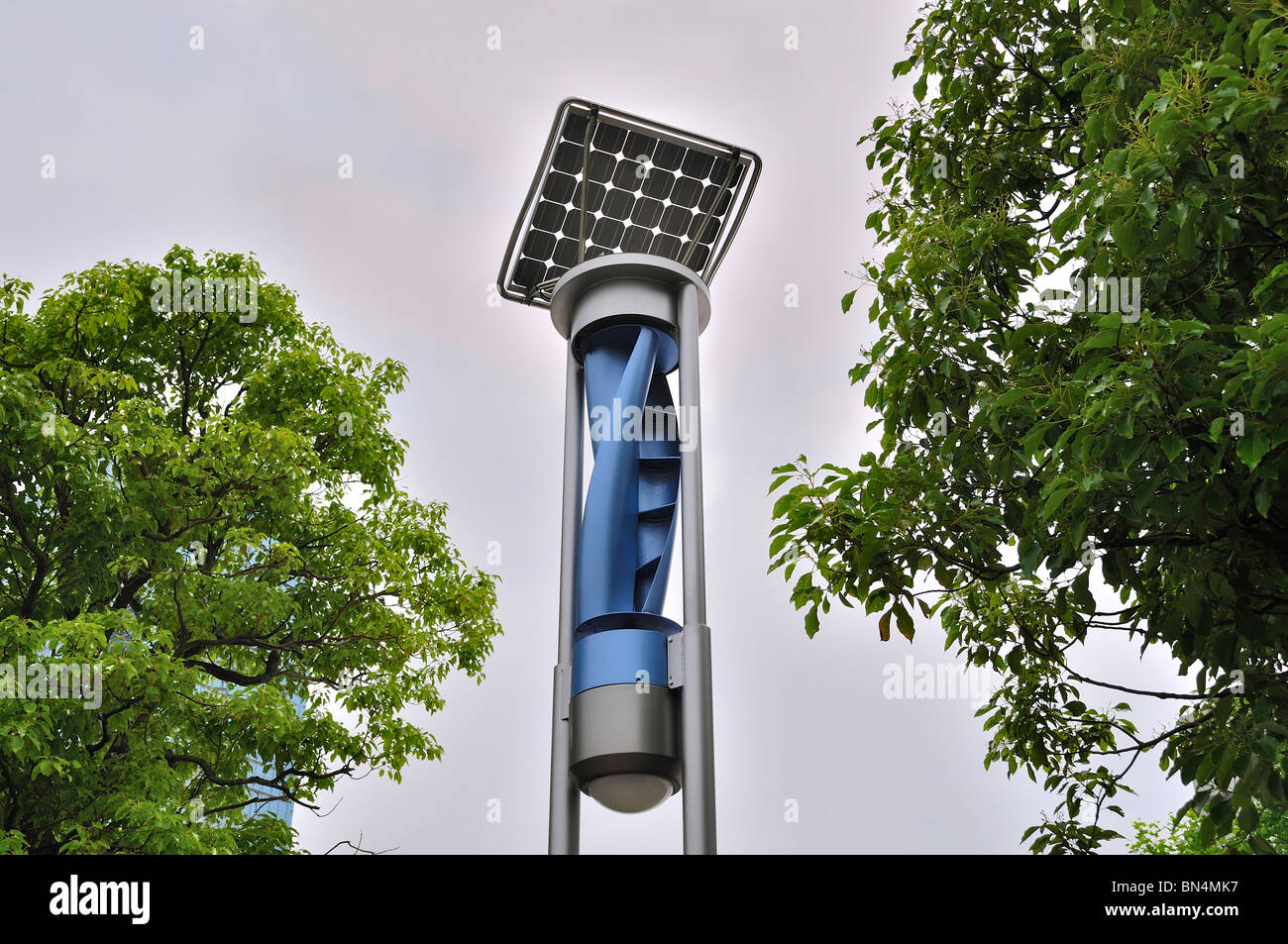 Niedrigen Winkel Schuss von Solar-Panel Straßenlaterne Pole zwischen grünen Bäumen gegen bewölktem Himmel (Japan) Stockfoto