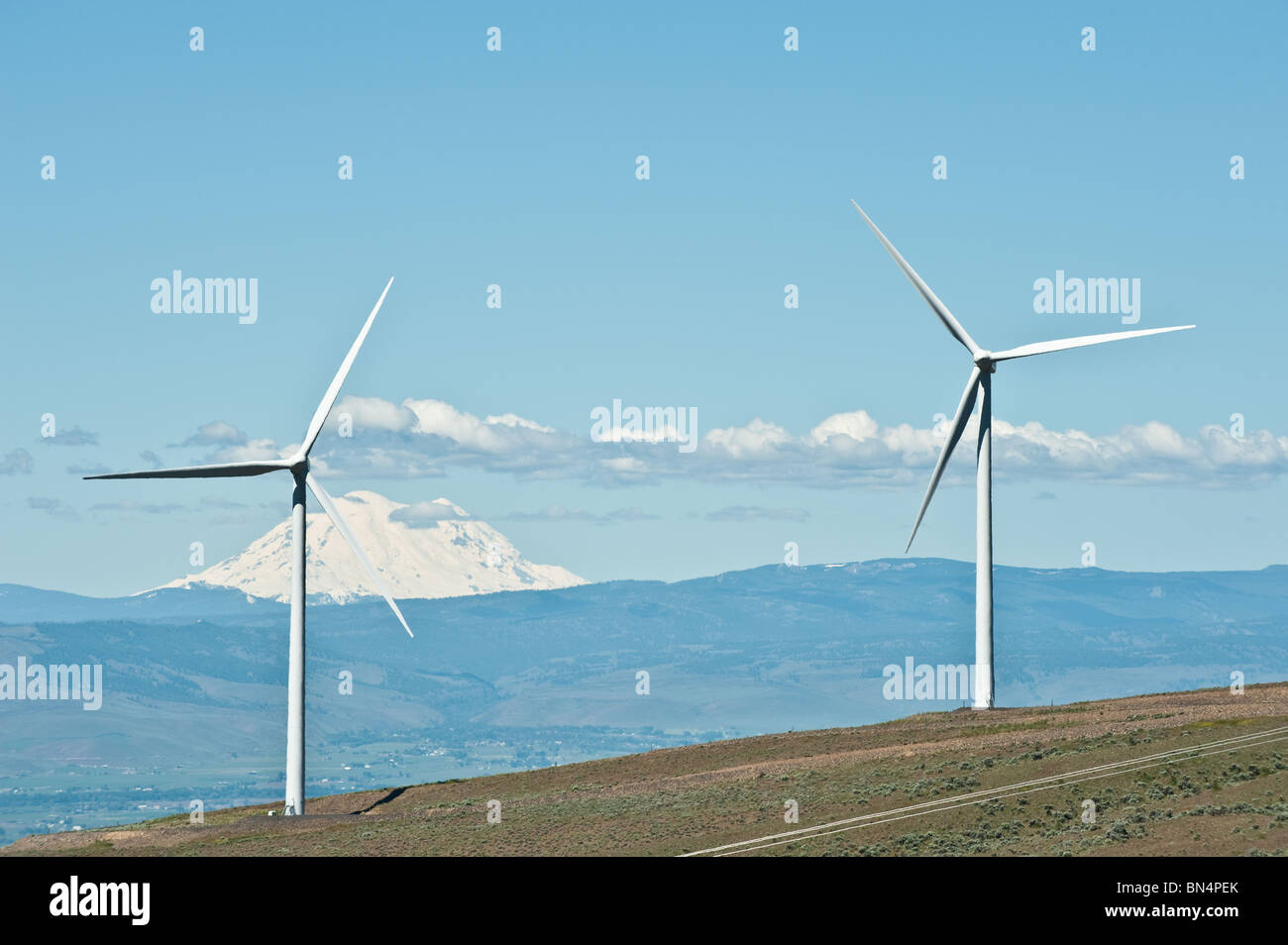 Riesige saubere Energie Windkraftanlagen auf einem Bergrücken mit einem schneebedeckten Berg im Hintergrund Stockfoto