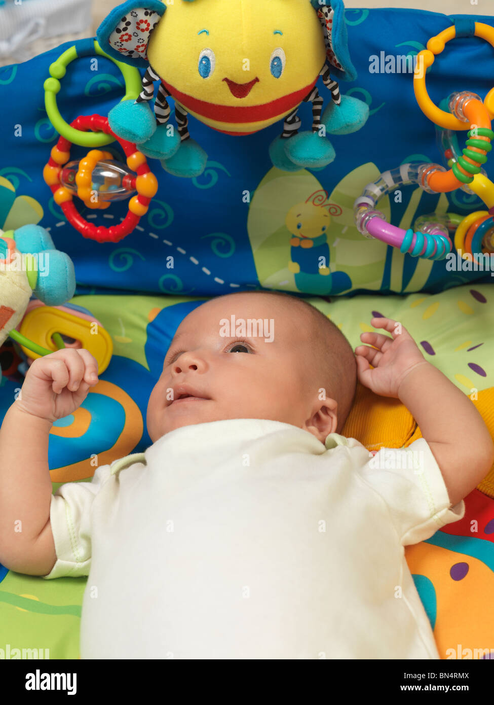 Sechs Wochen alten niedlichen Baby junge liegend in eine bunte Spielmatte mit Spielzeug Stockfoto