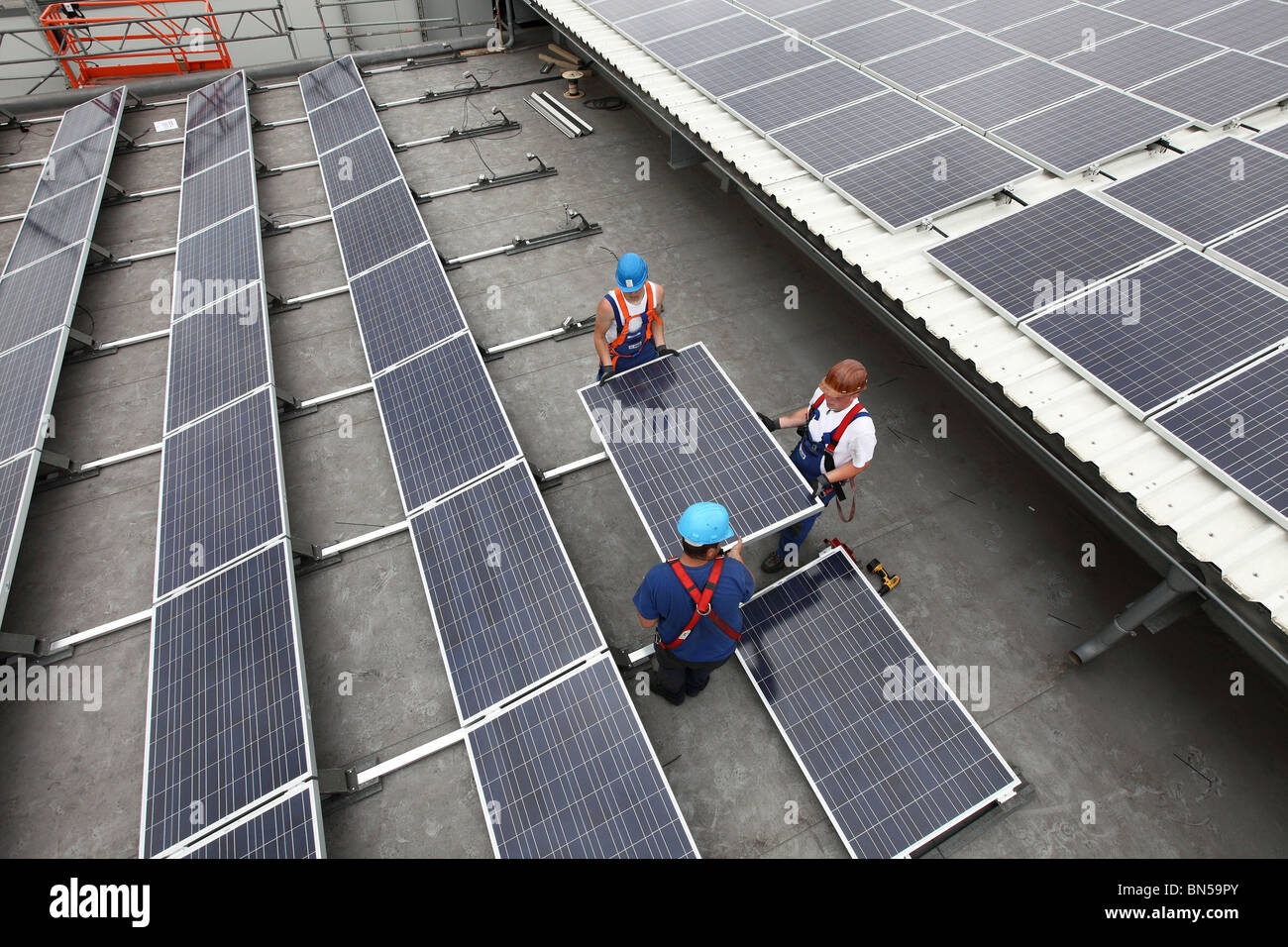 Bau einer großen Solaranlage auf einem riesigen Flachdach einer Lagerhalle. Stockfoto