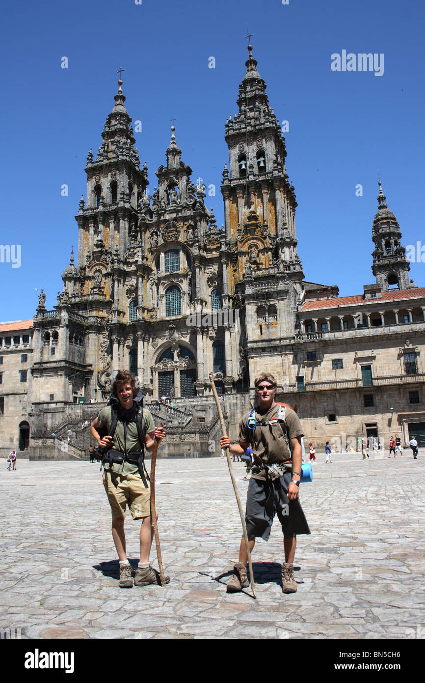 Zwei Pilger mit Rucksäcken und Mitarbeiter stehen vor der Kathedrale, Santiago de Compostela, Galicien, Nordspanien. Stockfoto