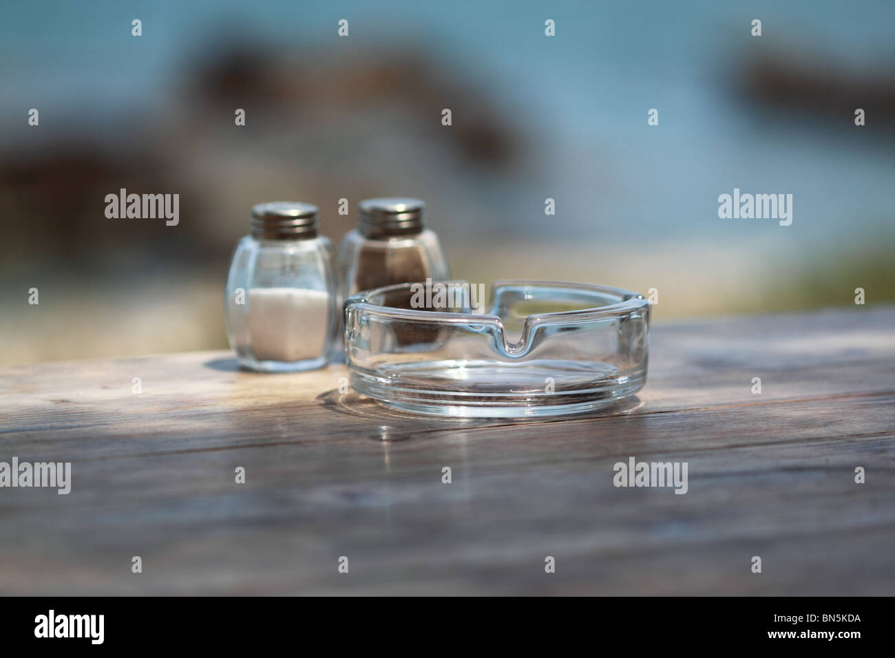 Aschenbecher, Salz und Pfeffer auf einem Holztisch Stockfoto