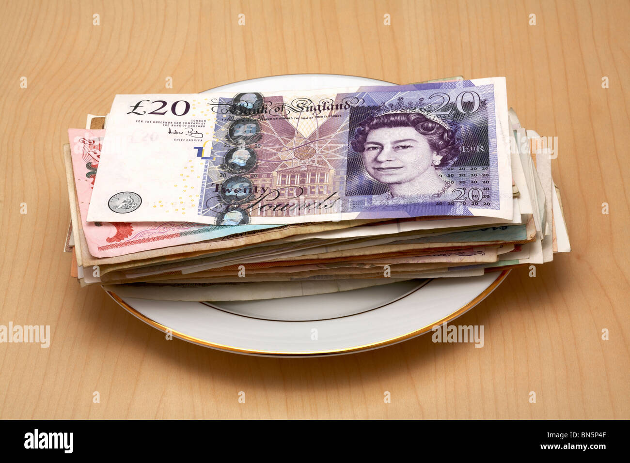 Porzellanteller mit UK £20-Pfund-Note drauf legen Stockfoto