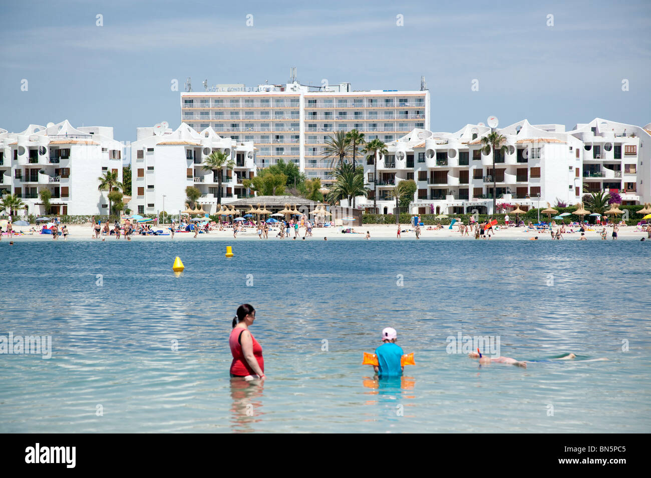 Ein Blick von Alcudia, Mallorca auf den Balearen mit Hotels und Menschen im Meer paddeln. Stockfoto
