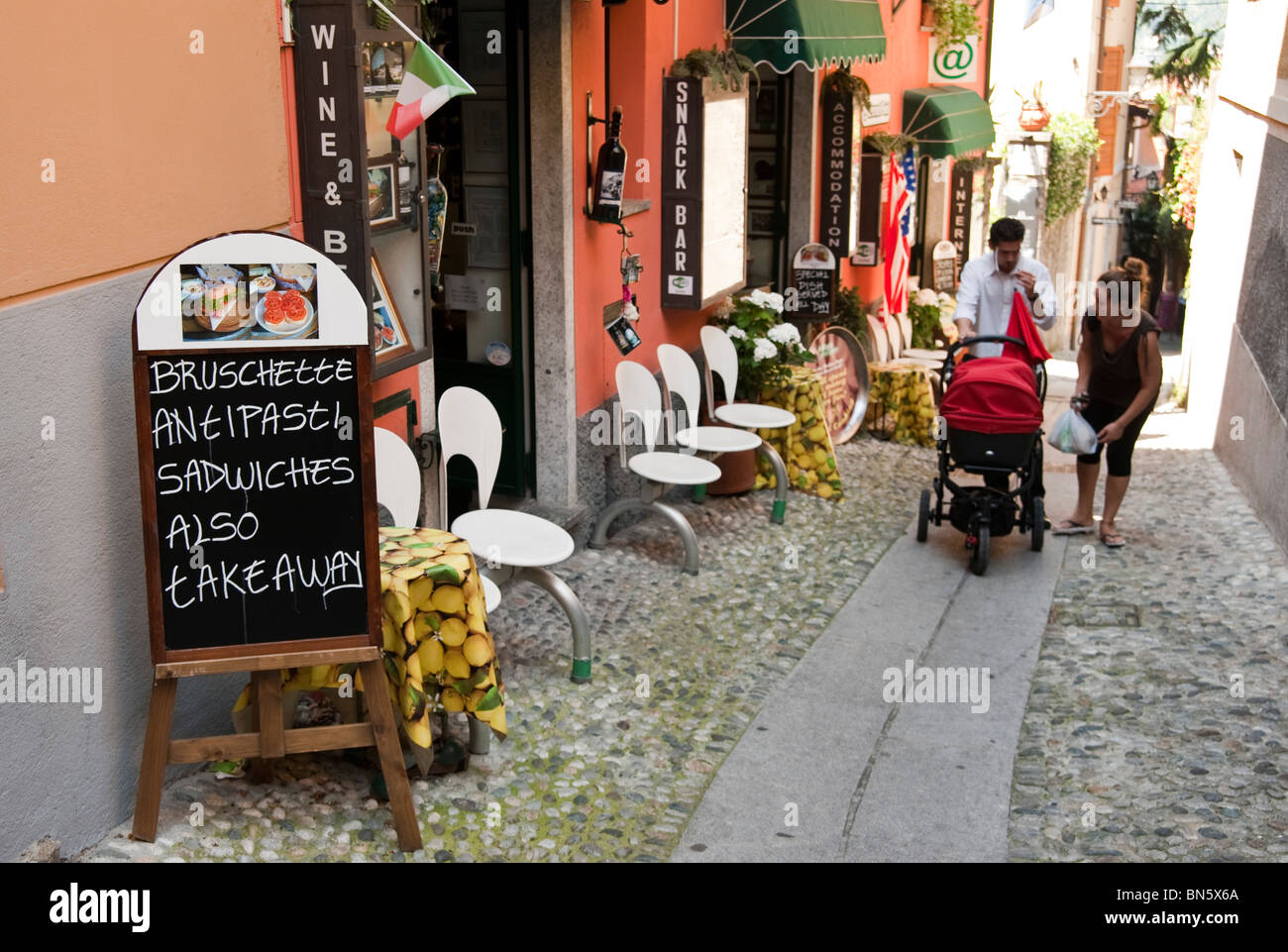 Eine junge Familie, die zu Fuß in einer gepflasterten Straße in Bellagio, Comer See, Italien Stockfoto