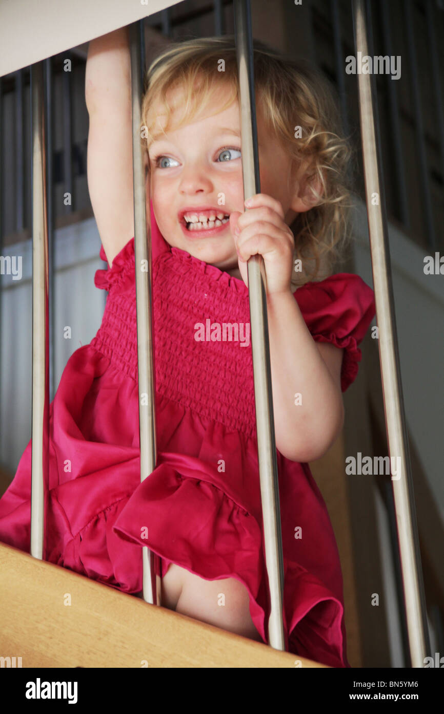 Mädchen Kleinkind saß auf der Treppe zu Hause lachen durch das Geländer Geländer Modell veröffentlicht Stockfoto
