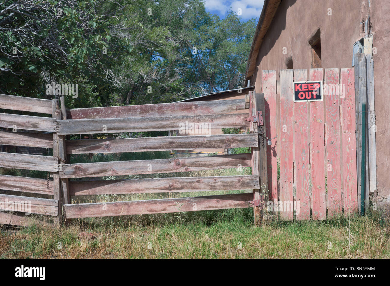 Eine alte verwitterte Holz Zaun und verschlossenen Tor mit einem Schild "KEEP OUT" gebucht, gefunden in den Seitenstraßen von Tularosa, New Mexico. Stockfoto