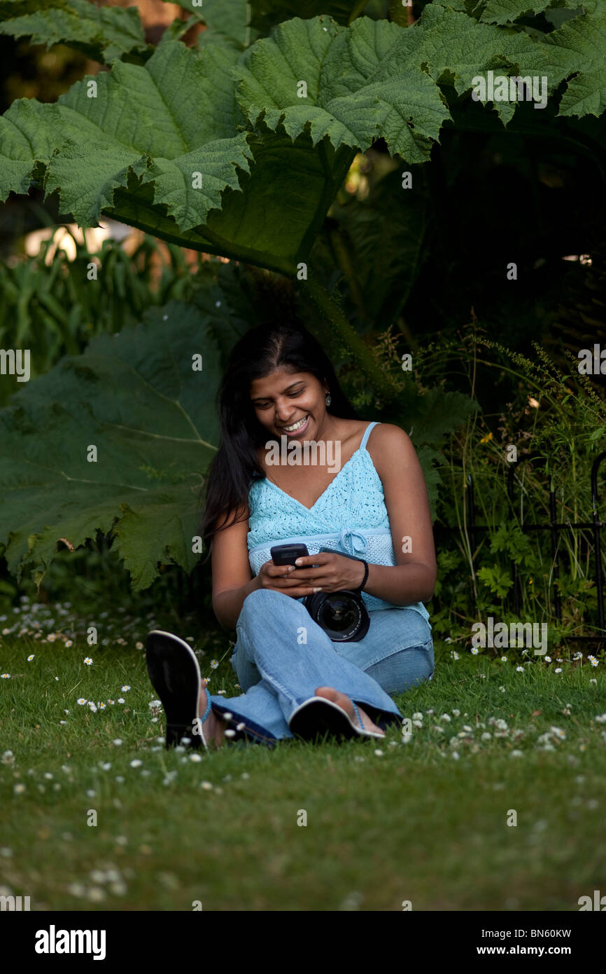 Frau mit Telefon unter Baum Stockfoto