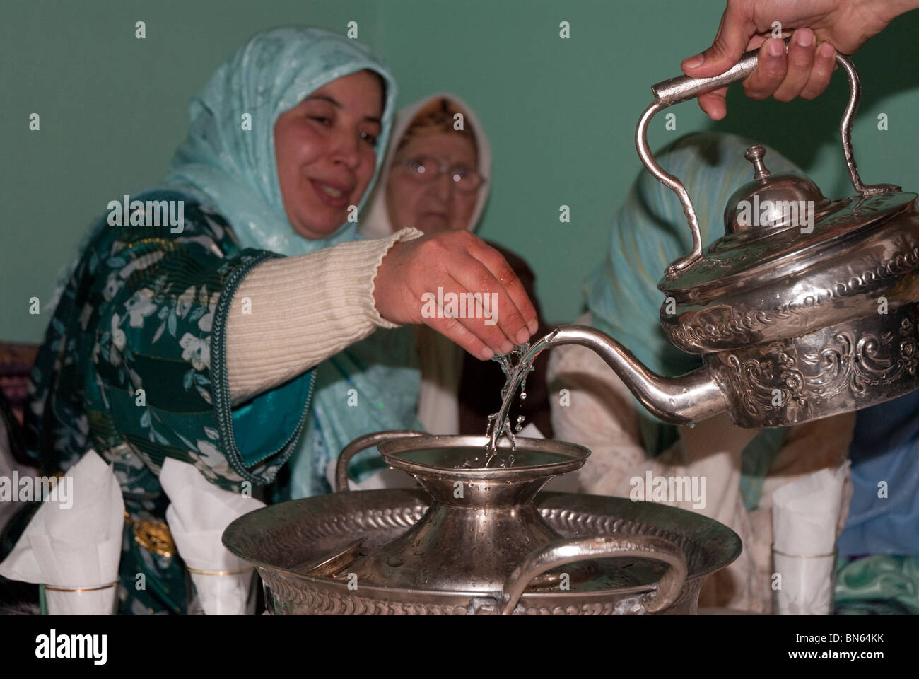 Eine marokkanische Frau wäscht ihre Hand vor dem Essen bei einer traditionellen Hochzeit in Sefrou. Stockfoto