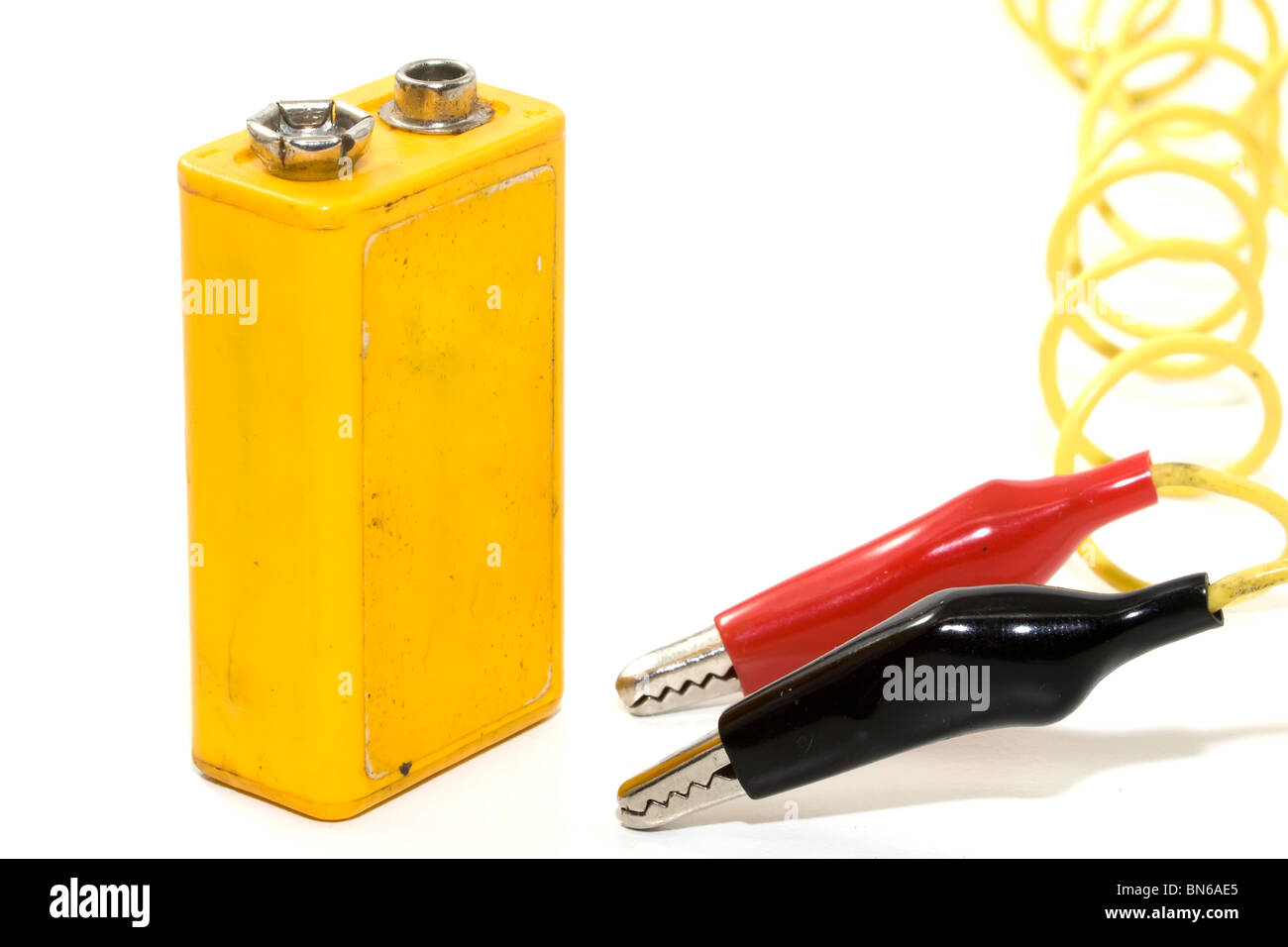 Gelbe 9 Volt Batterie isoliert auf weißem Hintergrund und rote und schwarze Klammern an Kabeln Stockfoto